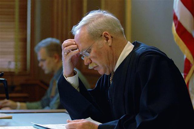 Photograph of State Supreme Court Judge Thomas McNamara, looking over documents in his courtroom, by Paul Buckowski/AP pool photo